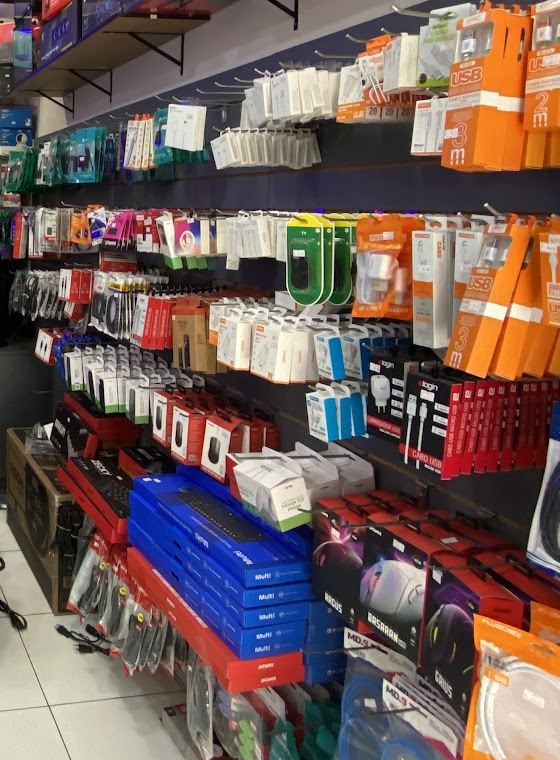Parede da loja com cabos, carregadores, mouses e teclados