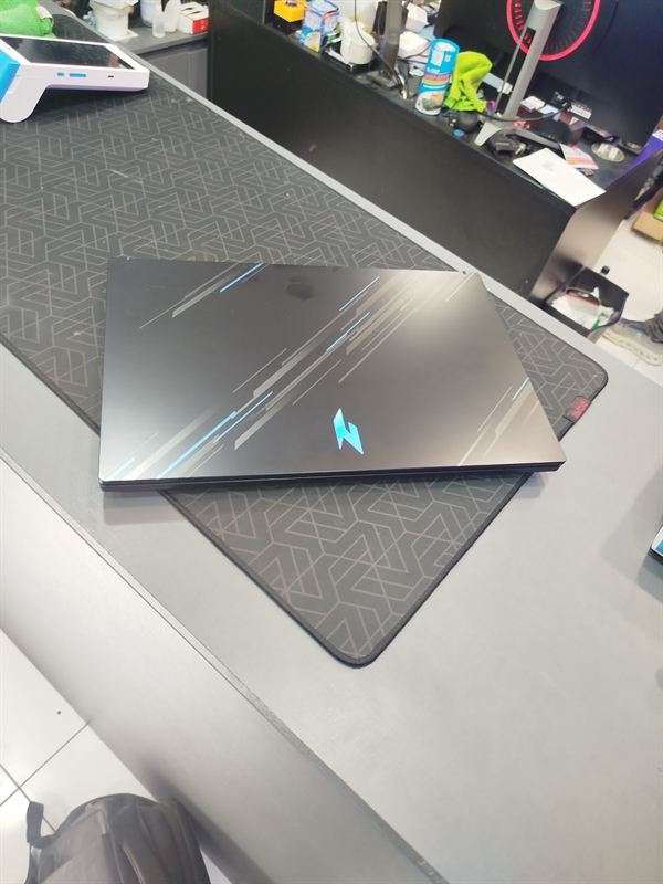 Notebook gamer Acer Nitro fechado sobre o tapete da bancada, com o logo azul na tampa