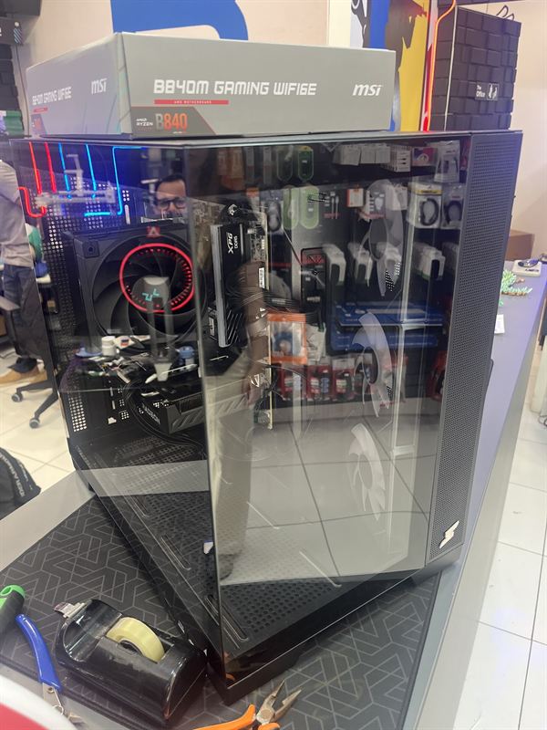 PC com placa-mãe MSI B840M Gaming WiFi 6E em gabinete de vidro, sobre a bancada da loja